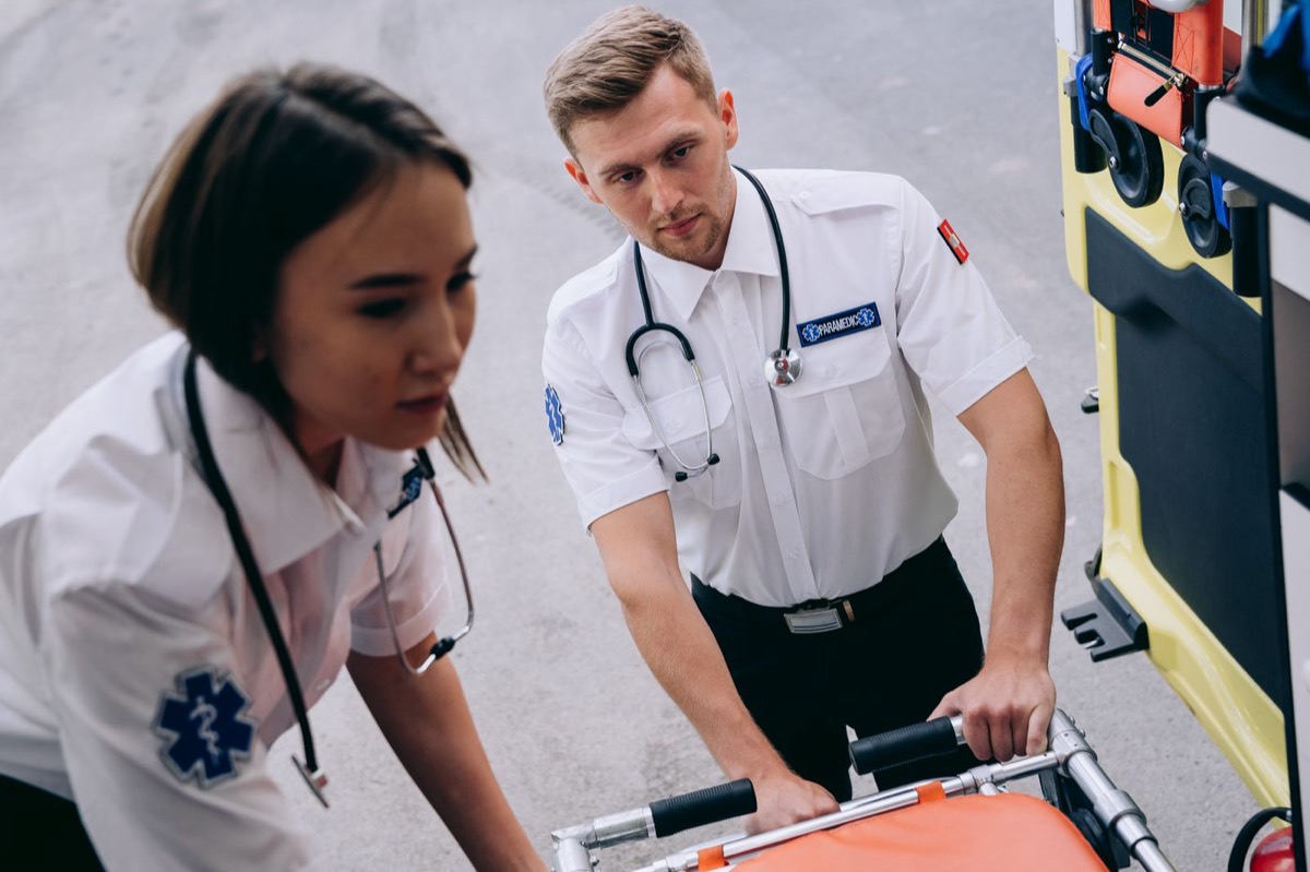 Two paramedics moving an ambulance stretcher